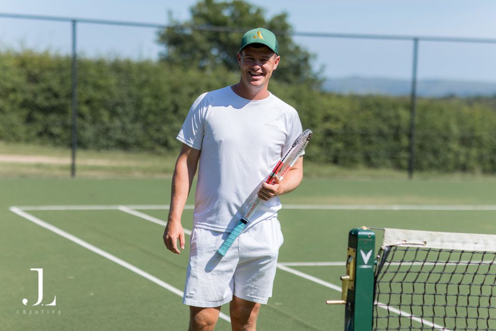 Man holding a tennis racket on a court during Belmond's luxury hospitality retreat.