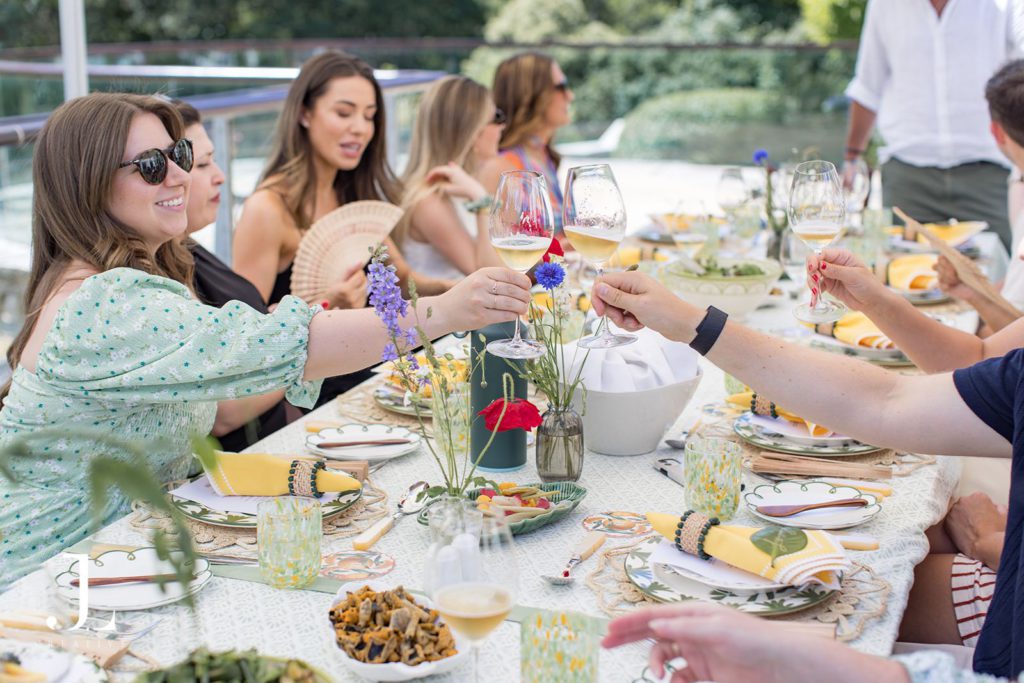 Guests toasting with French Bloom sparkling wine at an outdoor dining table.