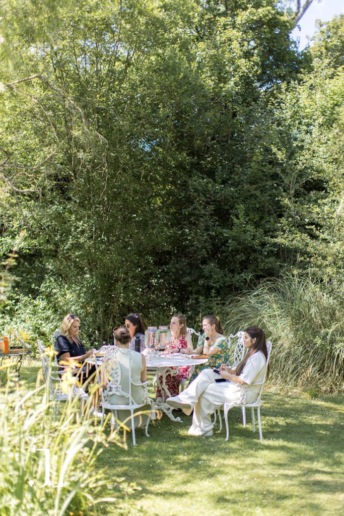 Guests seated around a white garden table in the shade at Knepp Estate retreat.