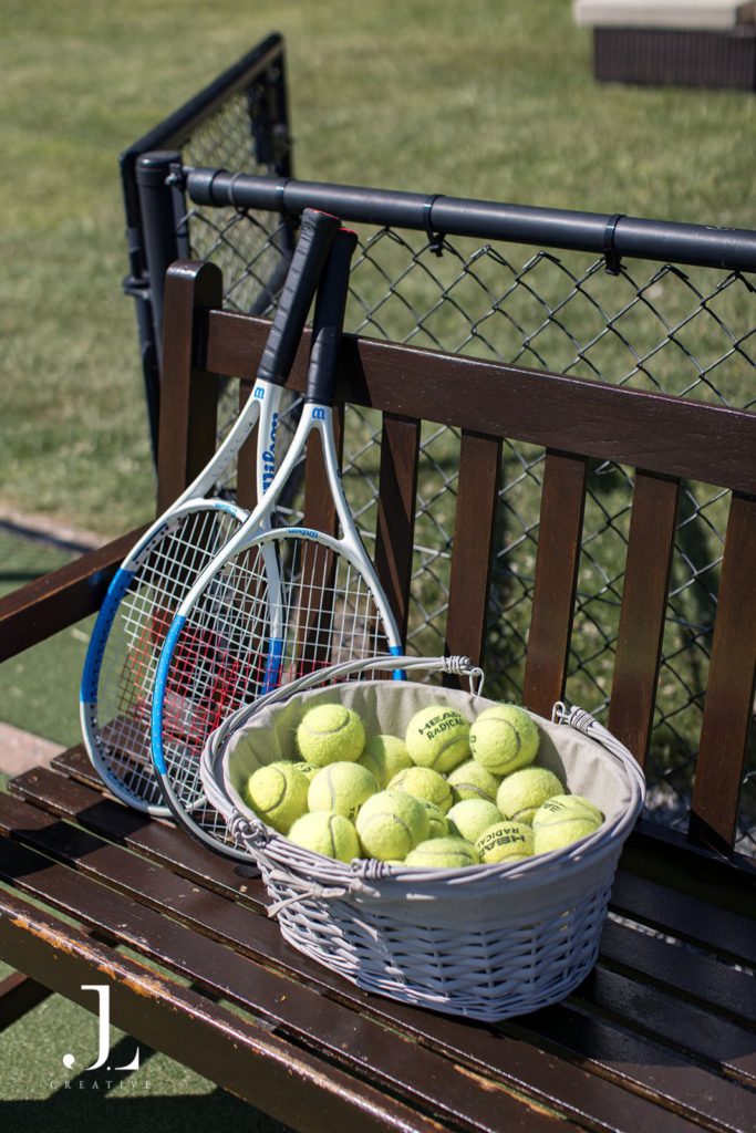 Tennis rackets and a basket of balls ready for guests on a bench at Knepp Estate.