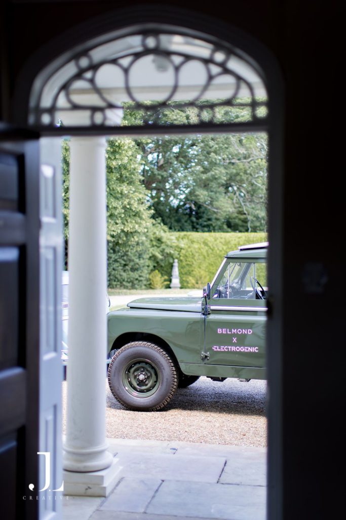 Green electric Land Rover framed by doorway at Knepp Estate during Belmond's luxury event.