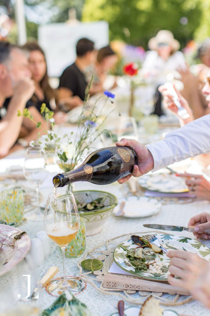 Sommelier pouring French Bloom non-alcoholic sparkling wine for guests at lunch.