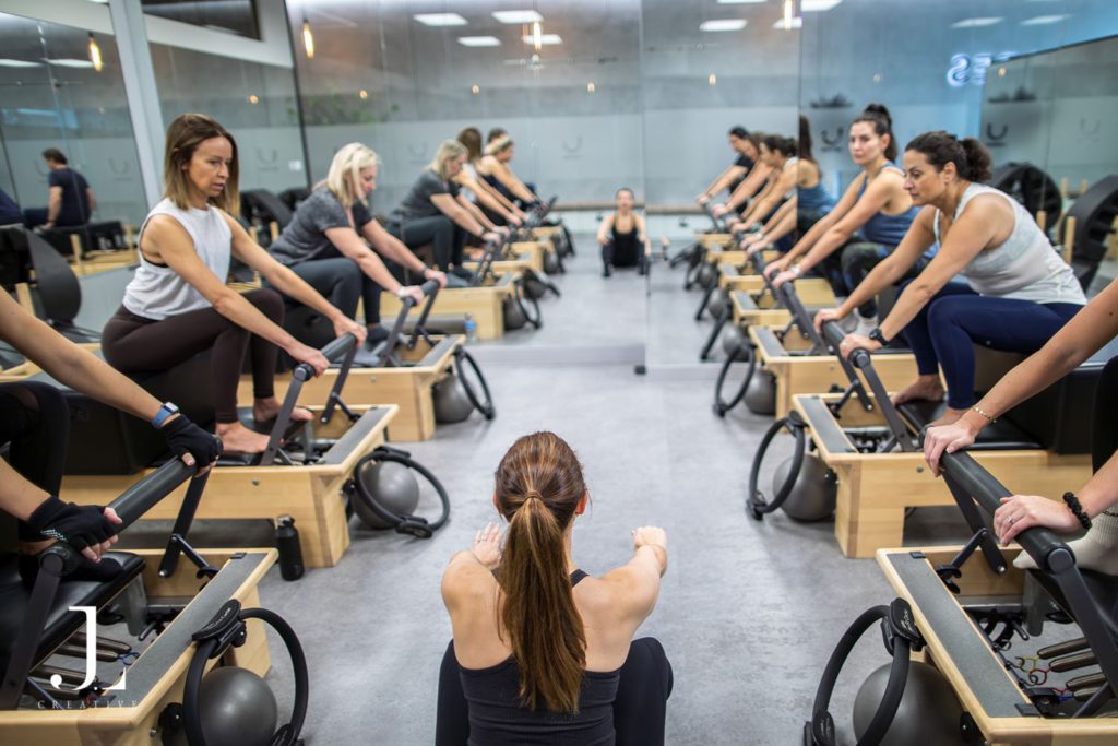 Instructor leading a full class of clients on reformers at You Pilates studio in Cobham.