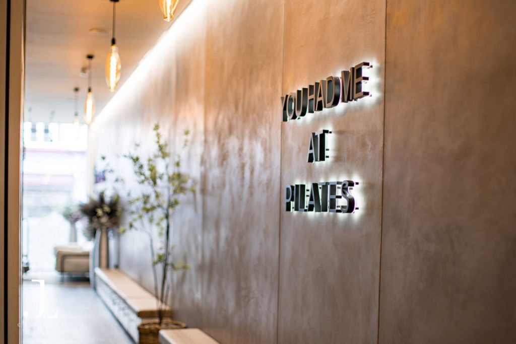 Illuminated sign reading You Had Me At Pilates inside You Pilates luxury studio in Surrey.