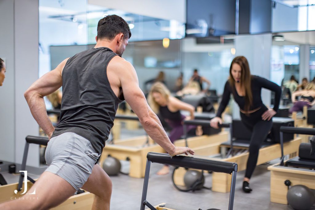 Male client executing a lunge movement on a reformer during a Surrey Pilates class photoshoot.
