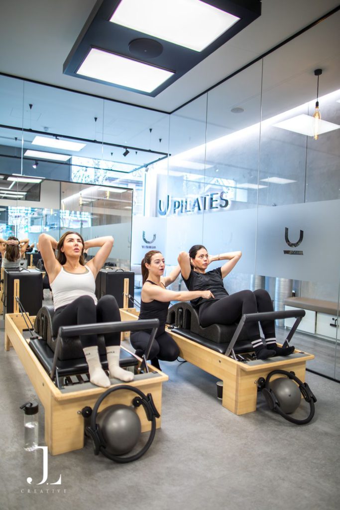 Pilates instructor giving hands-on posture corrections during a reformer class in Cobham.