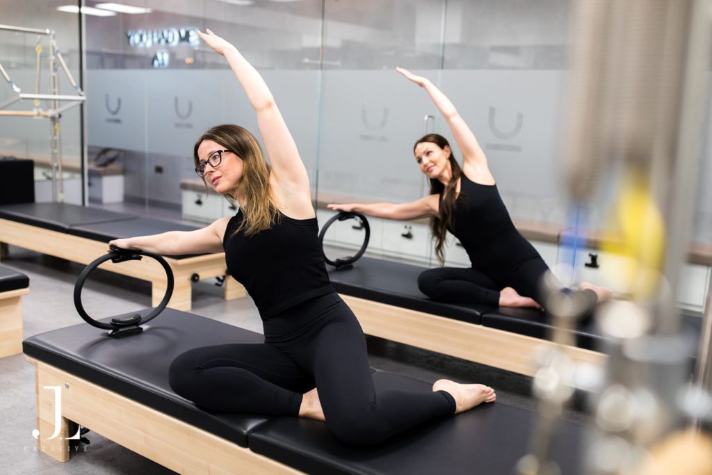 Two women doing side stretch poses with Magic Circles at You Pilates in Cobham