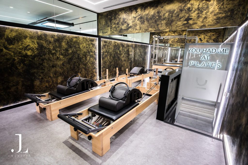 Empty luxury Pilates studio space featuring custom gold walls and reformers in Cobham.