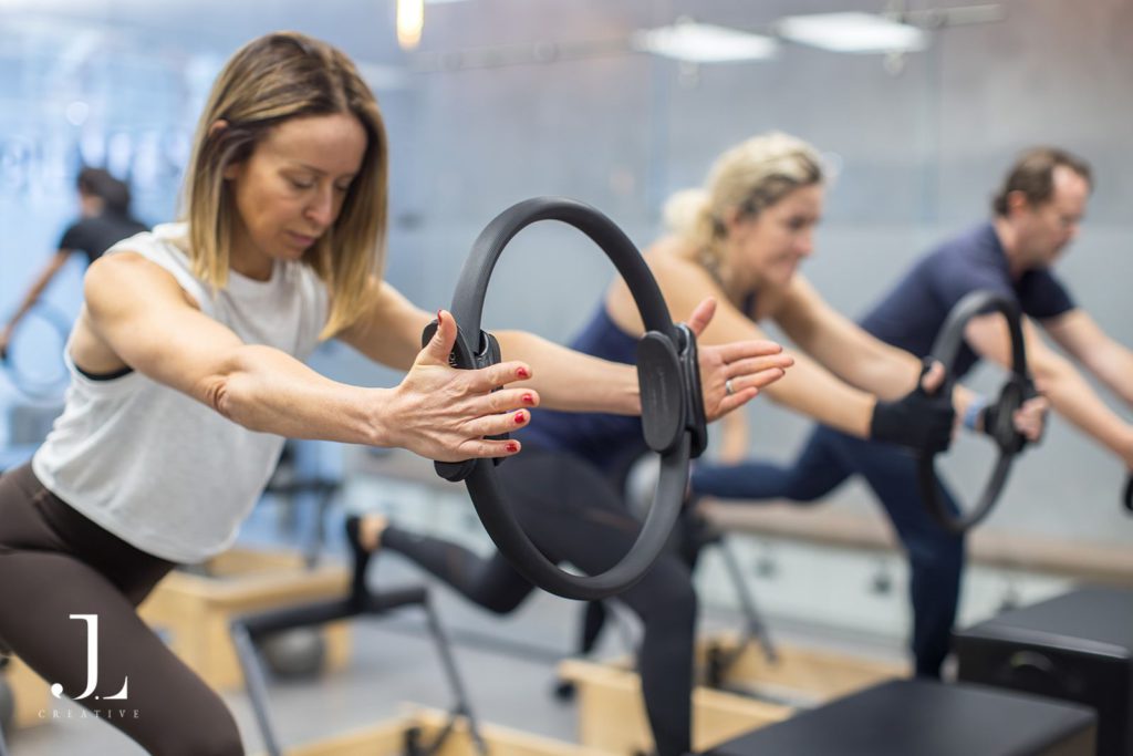 Clients using Magic Circle rings during a dynamic reformer class in Surrey.