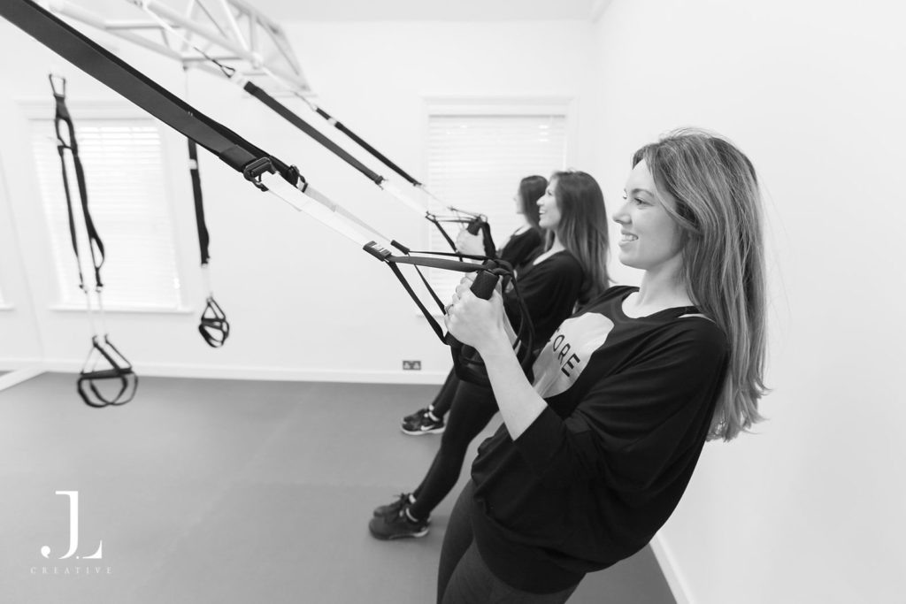 Clients training with suspension straps during a Pilates studio photography session in Surrey.