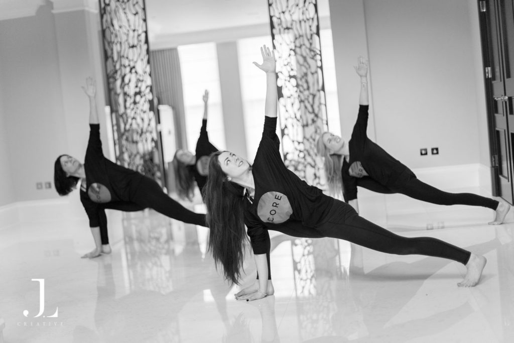 Group performing a dynamic side-plank stretch during Pilates studio photography in Surrey.