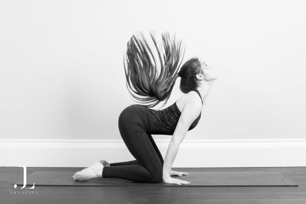 Woman performing a dynamic back arch movement on a mat during Pilates studio photography in Surrey.