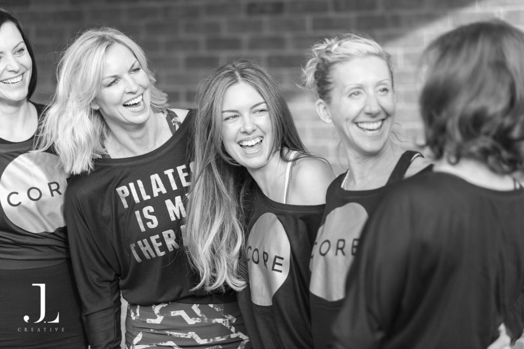 Candid moment of clients laughing together during a lifestyle Pilates studio photography shoot in Surrey.